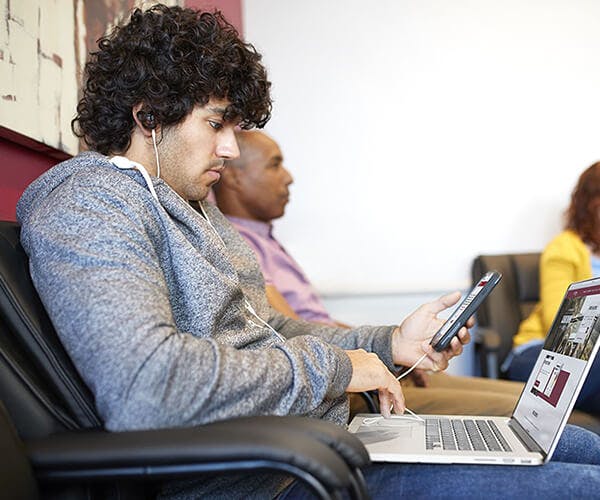 Man on phone and laptop in waiting room