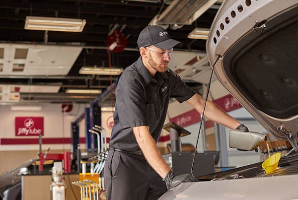 Jiffy Lube employee changing oil with Pennzoil