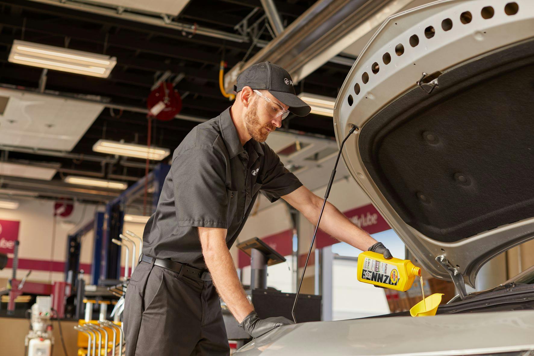 Jiffy lube technician performing routine maintenance by changing a vehicle's oil.