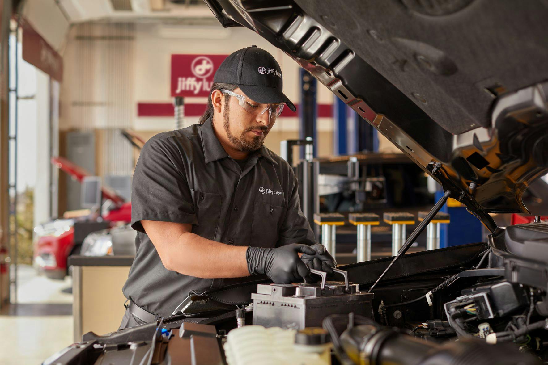 Jiffy Lube service member checking the strength of a car battery that displays weak car battery symptoms