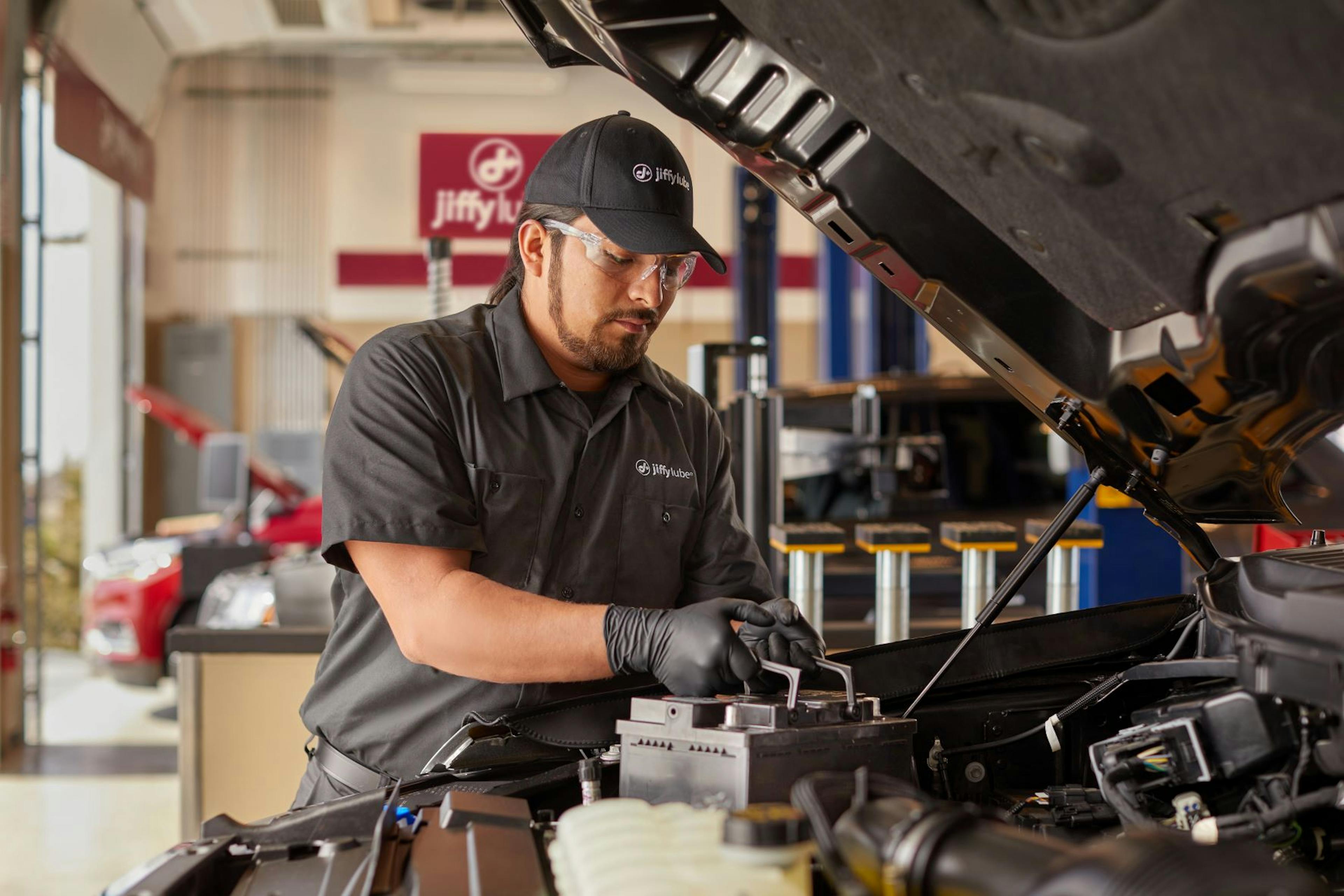 Jiffy Lube service member checking the strength of a car battery that displays weak car battery symptoms