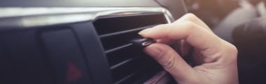 hand adjusting air vent in car