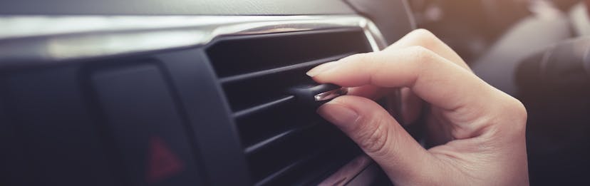 hand adjusting air vent in car