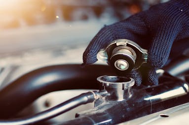 Jiffy Lube technician taking the cap off of radiator fluid