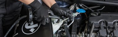 Jiffy Lube technician topping off windshield wiper fluid during an auto service