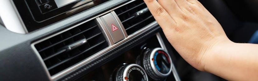 Hand in front of A/C vent testing air temperature