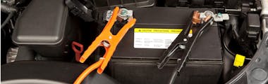 Cables connected to a car battery terminals for a testing a battery's strength