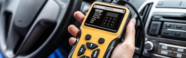 A technician runs a car diagnostic test using their handheld device
