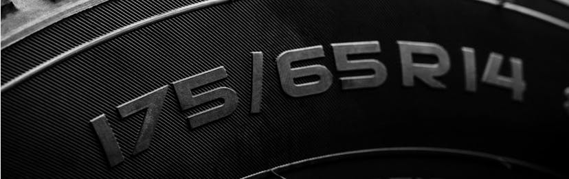 Close up on a new tire showing the tire size, aspect ratio, and wheel size