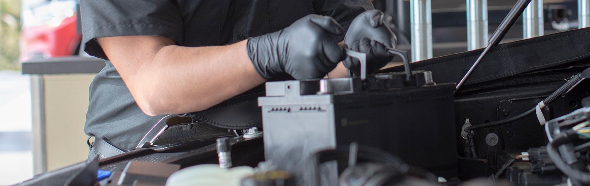 A Jiffy Lube technician replacing a dead battery with a new car battery