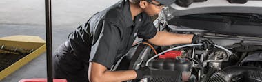 A Jiffy Lube technician replacing a vehicle's transmission fluid